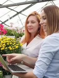 Medewerkster presenteert polycarbonaat tuinkas platen aan potentiele klant met laptop